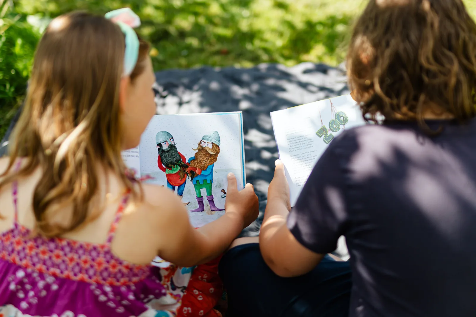 Zwei Kinder lesen gemeinsam in einem Buch im Außenbereich der GGS Auf dem Höchsten